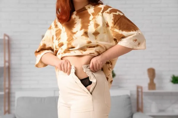 Image of woman trying to do her trousers up after pregnancy weight gain Wentworth