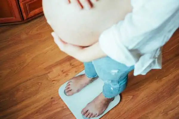 Image of woman weighing herself and experiencing weight gain through pregnancy Wentworth